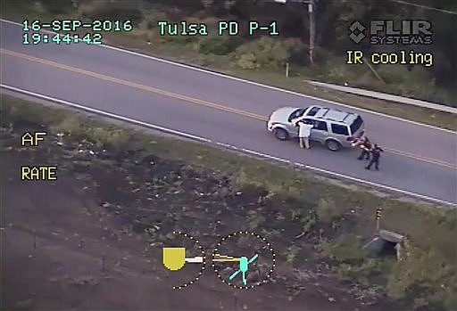 In this photo made from a Sept. 16, 2016 police video, Terence Crutcher, left, with his arms up is pursued by police officers as he walks next to his stalled SUV moments before he was shot and killed by one of the officers in Tulsa, Okla. (Tulsa Police Department via AP, File)