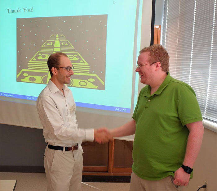 Zachary Feinstein, left, shakes hands with a student after his presentation on the economy of "Star Wars" last week during the Hancock Symposium.
