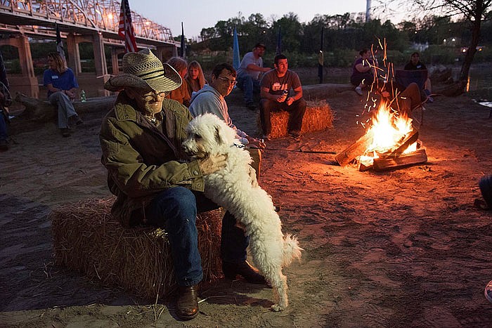 Joe Wilson is greeted by his dog, Teddie, last April after Wilson was released from the hospital after a long stay. Wilson was so happy to be surrounded by friends, a camp fire and his canine friends. Wilson and friends were on the sandy beach of the Missouri River the night before a scheduled canoe race the following morning.