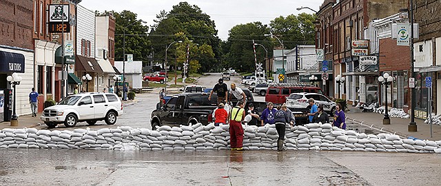 Volunteers build a sandbag barrier Thursday as the Shell Rock River rises over West Traer Street in downtown Greene, Iowa. Heavy rain runoff and flooding from the Shell Rock River forced the evacuation a few homes in Greene County in northern Iowa, as well as rescues at five homes.