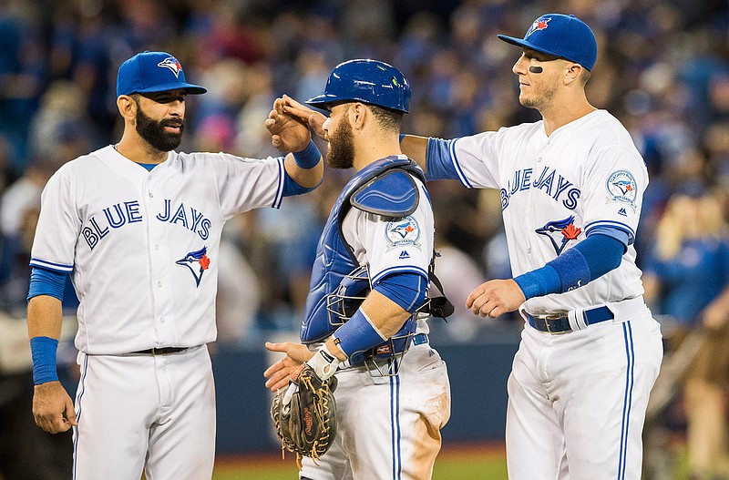 Toronto Blue Jays', from left to right, Jose Bautista, Russell Martin, and Troy Tulowitzki celebrate their team's win over the New York Yankees in a baseball game in Toronto, Friday, Sept. 23, 2016. 