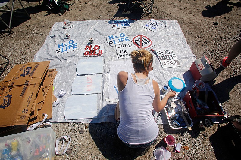 Casey Stinenetz of St. Louis paints signs against the Dakota Access Pipeline for people to hold during a protest against the pipeline which took place at a pipeline construction site Saturday Sept. 17, 2016, in Montrose, Iowa.