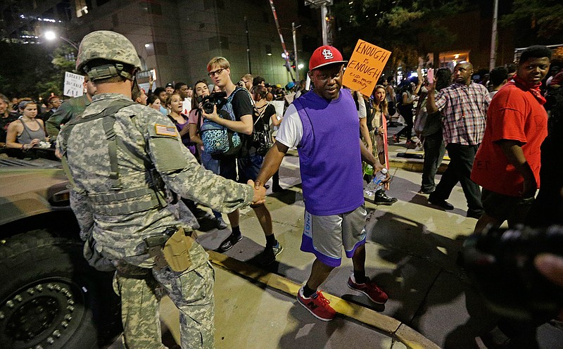 A protester greets a member of the North Carolina National Guard as they march in the streets of Charlotte, N.C. Friday, Sept. 23, 2016 to protest Tuesday's fatal police shooting of Keith Lamont Scott. 