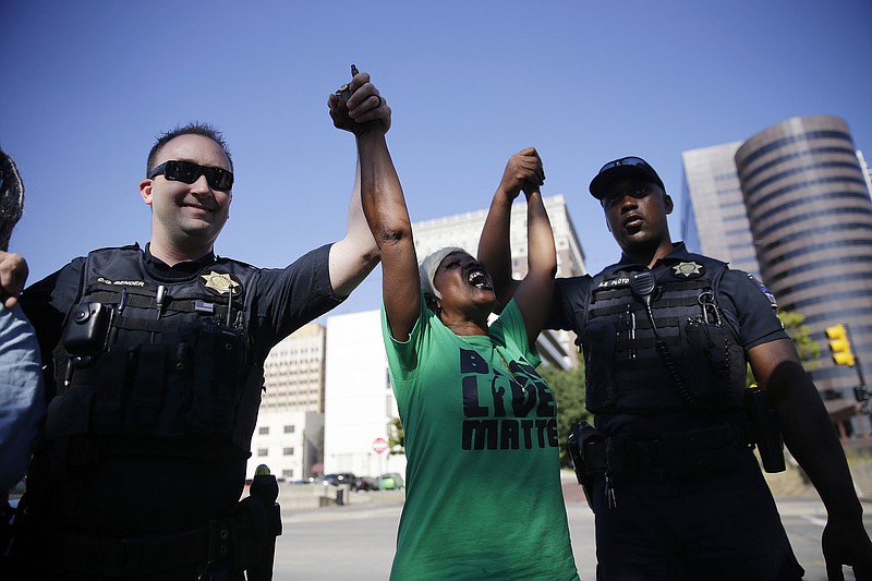 In this Thursday, Sept. 22, 2016 photo, Angie Pitts, of Tulsa, holds hands with Tulsa Police officers while protesting the death of Terence Crutcher, who was shot by police, in front of the Tulsa Country Courthouse, in Tulsa, Okla. 