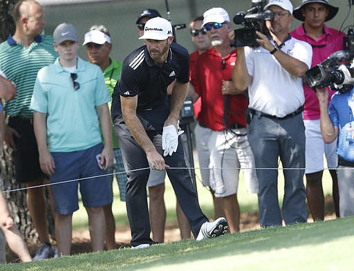 Dustin Johnson moves the rope before hitting from the rough on the 13th fairway during the third round of play at the Tour Championship golf tournament at East Lake Golf Club on Saturday, Sept. 24, 2016, in Atlanta.