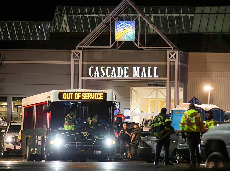 Emergency personnel stand in front of an entrance to the Cascade Mall at the scene of a shooting where several people were killed Friday, Sept. 23, 2016, in Burlington, Wash. Police searched Saturday for a gunman who opened fire in the makeup department of a Macy's store at the mall north of Seattle, killing several females, before fleeing toward an interstate on foot, authorities said.