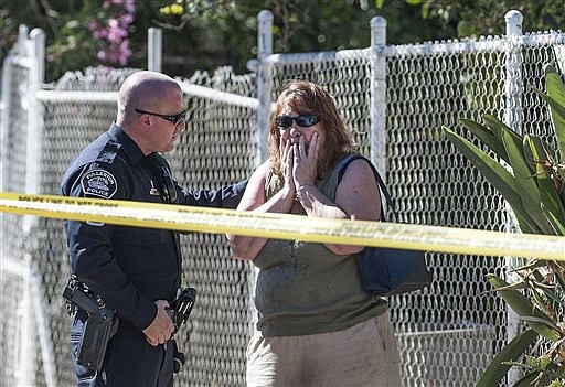 A Fullerton police officer comforts an unidentified woman outside a house where three adult bodies were found in Fullerton, Calif., Saturday, Sept. 24, 2016. Police officers found two men and a woman dead in the house after a child called 911. (Nick Agro/The Orange County Register via AP)