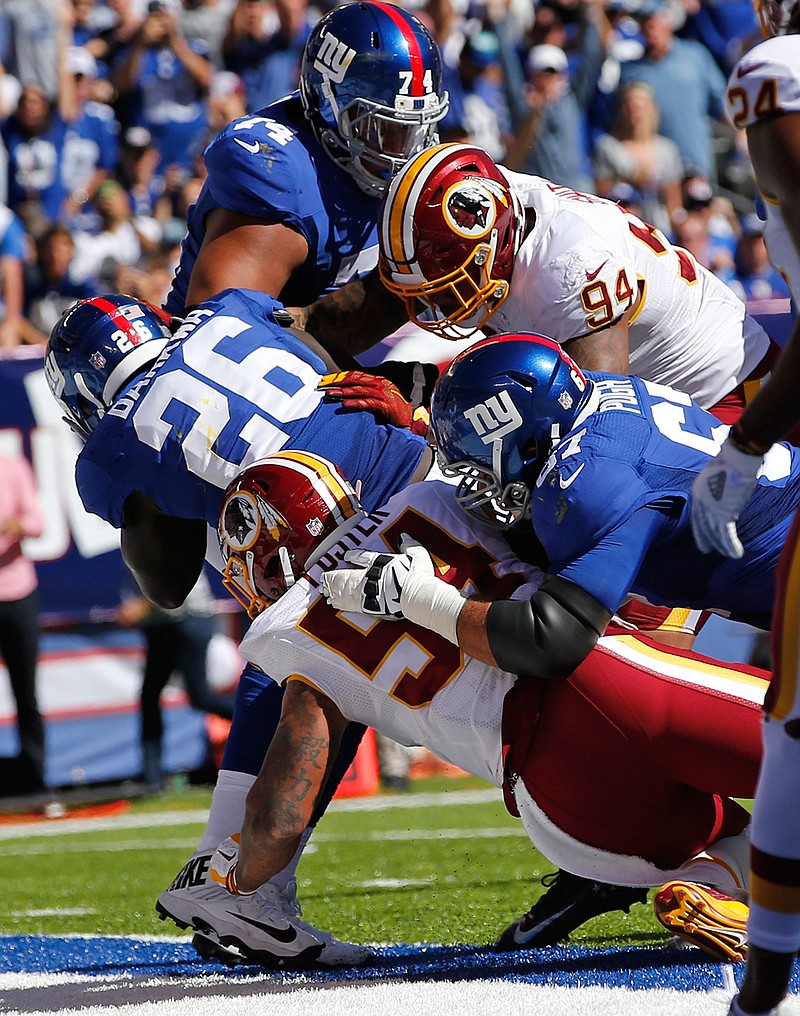 New York Giants running back Orleans Darkwa (26) is tackled in the end zone by Washington Redskins' Mason Foster (54) and Preston Smith (94) as he scores a touchdown during the first half of an NFL football game, Sunday, Sept. 25, 2016, in East Rutherford, N.J. 