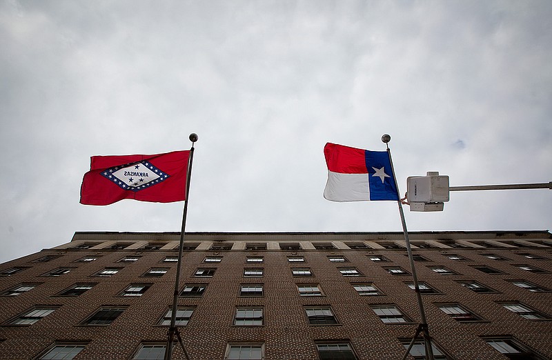 Mike McCatherine, a sign and signal technician with the city of Texarkana, Texas, hangs the Texas state flag Tuesday morning on the front of the Hotel Grim. Main Street Texarkana is hosting the second annual Dine on the Line fundraiser this Saturday along North State Line Avenue in downtown Texarkana.