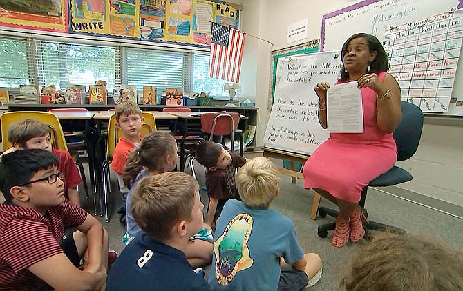 In this Sept. 13 still image from video, Kimberly Coleman-Mitchell, right, teaches her fourth-grade class at Oakridge Elementary School in Arlington, Virginia. Elementary schools in Arlington, South Burlington, Vermont, and Holyoke, Massachusetts, are among those that went homework-free at the start of the school year.