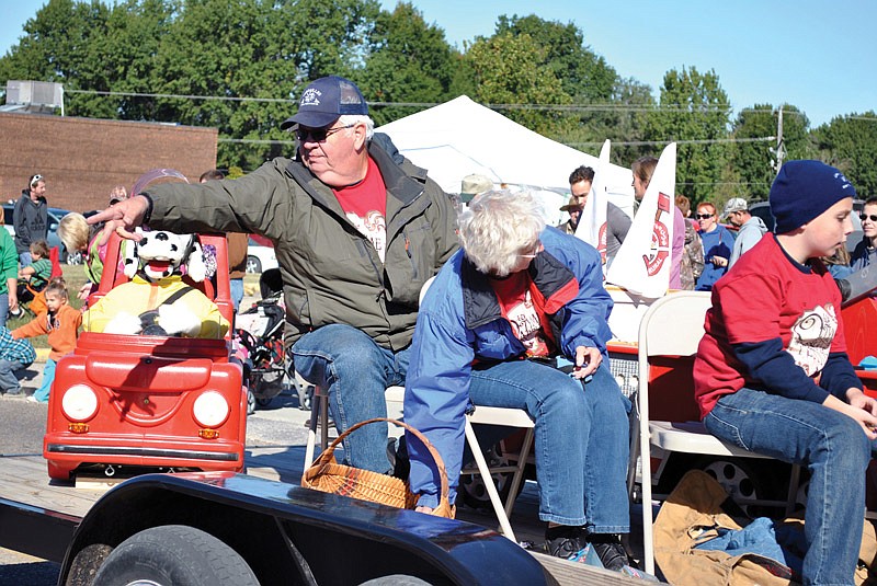 The 2015 Olde Tyme Apple Festival parade grand marshals, Doc and Carol Jones, wave and toss candy to spectators.