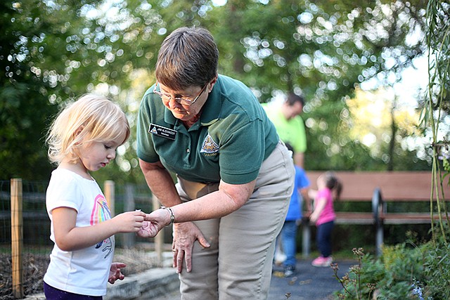 Volunteer Jan Alexander gives Kate Keubler, 2, a flower to smell Thursday while learning about nature at Runge Conservation Nature Center. Several Special Learning Center students attended for an optional after school program.