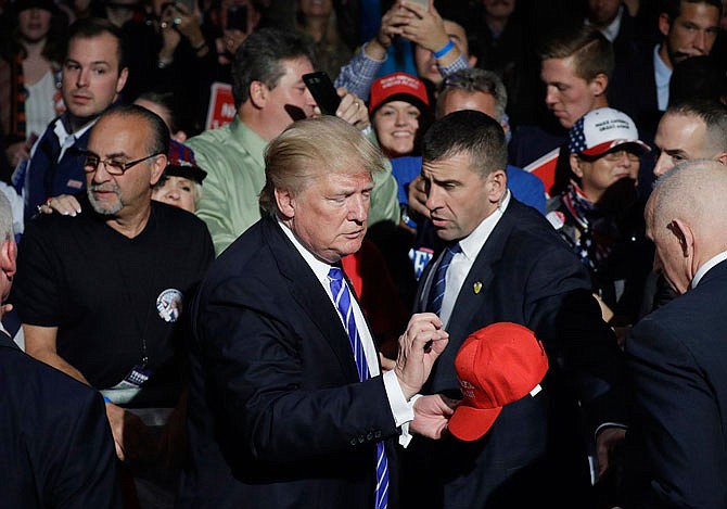 Republican presidential candidate Donald Trump signs a hat after a rally Friday in Novi, Michigan.