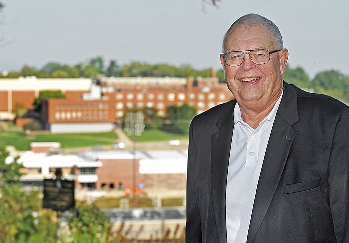 Chris Straub poses for a photograph with Jefferson City High School, where he served as superintendent from 1989-1997, in the background.