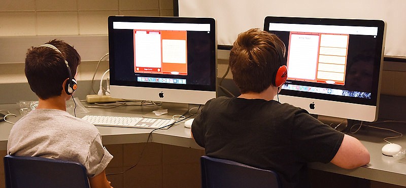 In this Sept. 30, 2016 photo, Brock Scholfield, left, and Quin Schepers, both students at Thomas Jefferson Middle School, wear headphones and follow verbal cues and instructions while taking a districtwide, kindergarten- through eighth-grade assessment for reading and math.