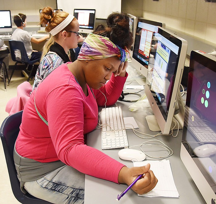 Thomas Jefferson Middle School student Monyae Taylor figures the answer to a math problem on paper as she listens to the instructions on earphones.