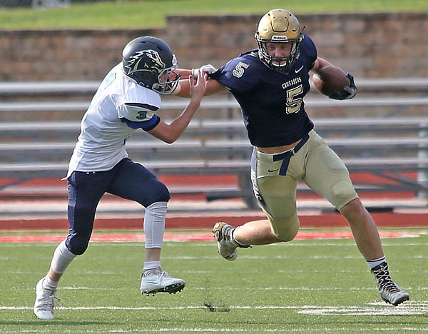 Nathan Bax of Helias fends off a tackle attempt by a Father Tolton player during a game last month at Adkins Stadium.