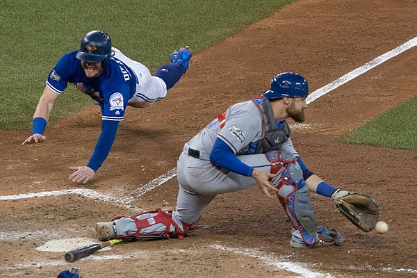 Josh Donaldson of the Blue Jays scores on a throwing error from Rangers second baseman Rougned Odor as catcher Jonathan Lucroy gathers up the ball during the 10th inning of Sunday's American League Division Series game in Toronto. The Blue Jays won 7-6 to sweep the Rangers in three games.