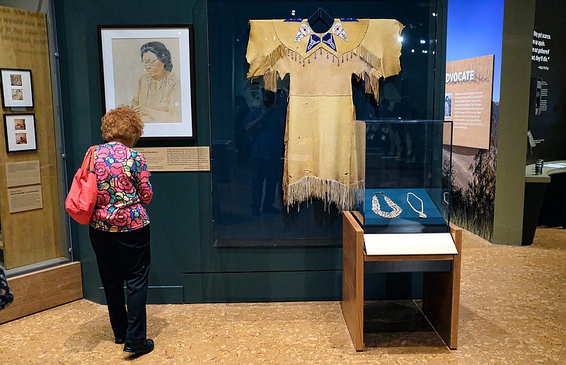 In this Thursday, Oct. 6, 2016 photo, a visitor views a display of a buckskin dress in the style of one work by Mabel McKay at the Autry Museum of the American West in Los Angeles. "The Life and Work of Mabel McKay," a Pomo Indian basket weaver, healer, civil rights activist and person believed to be the last speaker of her tribal language when she died in 1993. Her intricately woven, often colorful baskets, ranging from the size of a pinhead to some large enough to serve as laundry containers, are accompanied by a recreation of her workroom, narration by her son and other works are part of the opening on Oct. 9.