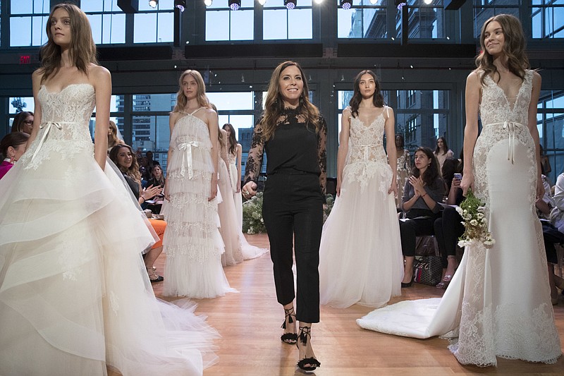 Designer Monique Lhuillier, center, stands with models wearing gowns from her bridal collection during bridal fashion week Oct. 7 in New York. 