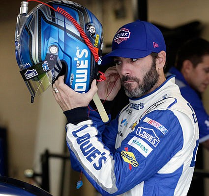 Jimmie Johnson prepares to don his helmet for a practice session Friday at Kansas Speedway in Kansas City, Kan.