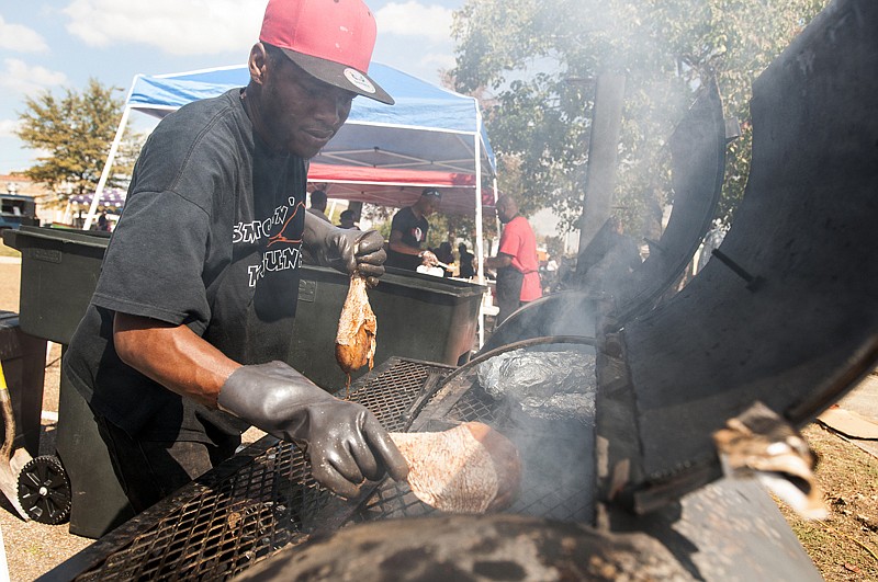 Kevin Douglas with KPK Cajun from Shreveport, La., puts some Cajun turkey legs on the grill Saturday during the Front Street Food Fest at the Front Street Festival Plaza. 