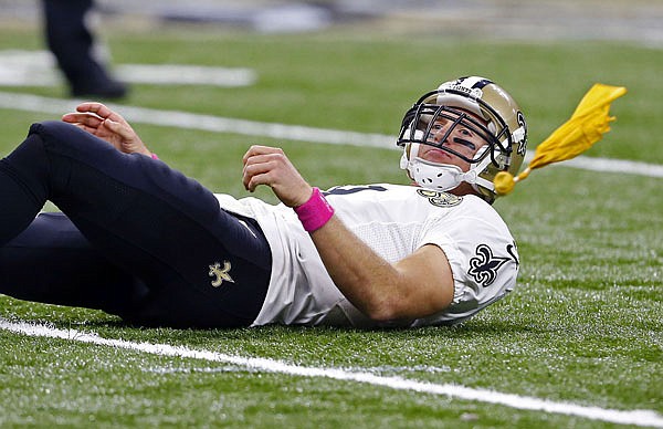 Saints quarterback Drew Brees lies on the ground as a penalty flag sails by after he released a touchdown pass in the second half of Sunday's game against the Panthers in New Orleans.