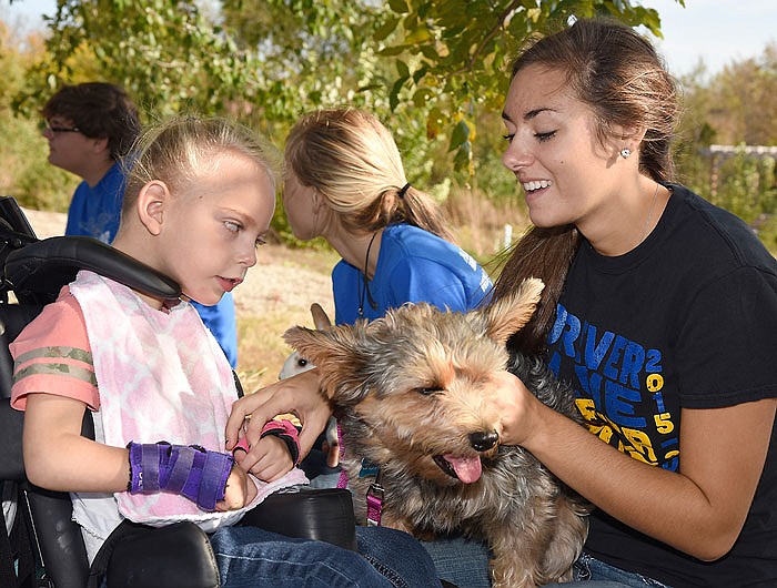 Leah Stichler, right, takes the hand of Charlotte Bickel to help her pet Bubba, the Yorkshire Terrier and Welsh Corgie Terrier mix. Stichler, a junior,  is a three-year member of Eldon High School's FFA program and was one of more than a dozen students who brought a petting zoo to the students of the Special Learning Center Monday.