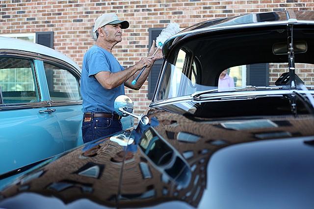 Ray Knott dusts off his 1950 Chevy Deluxe two-door at Baymont Inn and Suites in Jefferson City on Tuesday. Vintage Chevrolet Car Club members took day trips throughout the area in their cars.