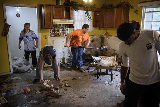 Fayetteville Christian School students and staff help clean out Cynthia Quick's flood damaged home, Friday, Oct. 14, 2016, in a Habitat for Humanity neighborhood in Fayetteville, N.C. Over 90 Habit for Humanity homes in Fayetteville were damaged by flooding from Hurricane Matthew flood. (Andrew Craft/The Fayetteville Observer via AP)