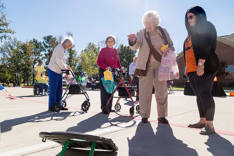 Virginia Boswell tosses a bean bag to win candy Friday at the LinRock Health and Rehab Center booth at the Fall Festival hosted by Hospice of Texarkana. The festival aimed to bring together organizations that serve the elderly so visitors can get the information they need in one place. 