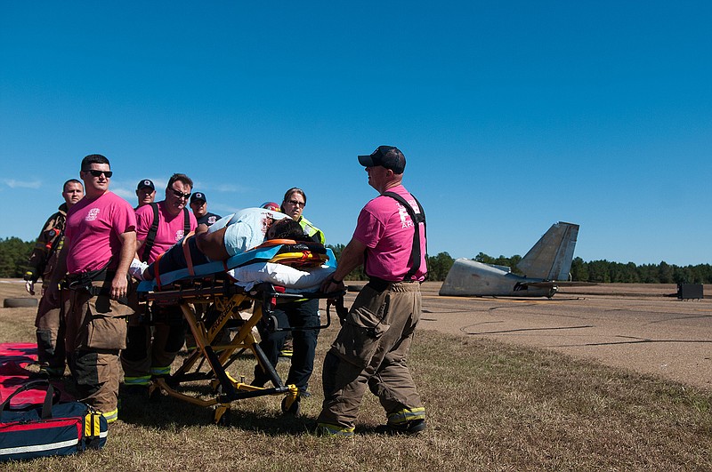 Local firefighters and first responders transport a victim during a mock airport emergency disaster drill Friday at the Texarkana Regional Airport. 