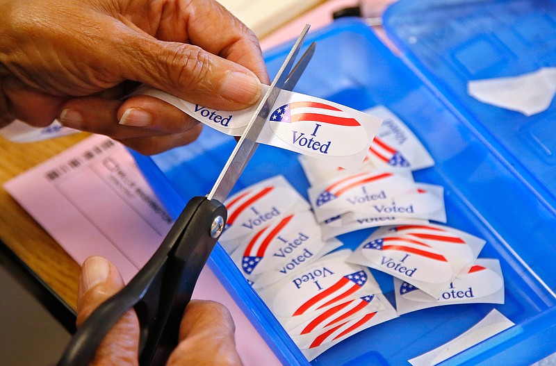 In this June 28, 2016 file photo, an elections clerk cuts from a strip of "I Voted" stickers at a polling place in Oklahoma City. Officials in Oklahoma, Texas and Louisiana say they've denied a request by Russian officials to be present at polling stations during next month's election. The U.S. State Department's spokesman says Russia hasn't participated in an international mission to observe elections, so its effort to do so on the state level represents "nothing more than a PR stunt." 