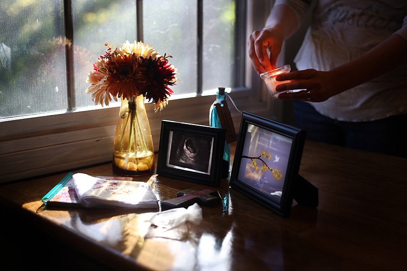 Jennifer Bish lights a candle next to an ultrasound and memorabilia of her daughter Saturday at her house in Russellville. Bish had a miscarriage and lost her daughter in 2014.