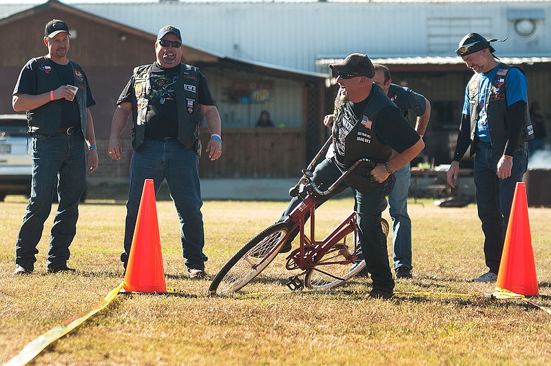 Joe Wilgeroth, right, laughs Saturday after falling off the "backward bike" while playing a variety of bike games during the third annual Texas Moose Rider Association Rally at Texarkana Moose Lodge 2282. Portions of the money raised from the event will help local organizations such as the Hero's Pantry. 