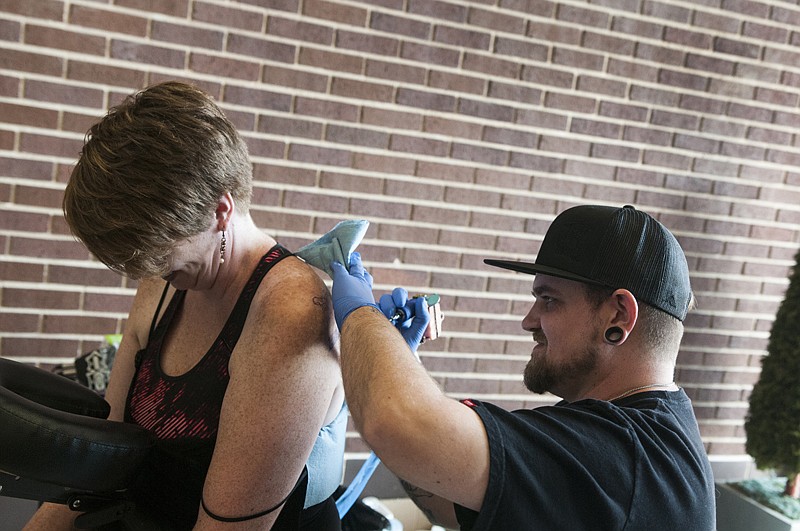 Kathy Williams, Texarkana A&M University-Texarkana vice president for student enrollment, gets a tattoo Monday by Texarkana Ink tattoo artist Thomas Wester. Williams said she would get a tattoo if the school met its enrollment goals for the year. 
