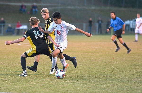 Erick Ortiz of the Jays maneuvers the ball past a pair of Sedalia Smith-Cotton defenders during Monday night's Class 4 District 11 semifinal match at Eddie Horn Field.