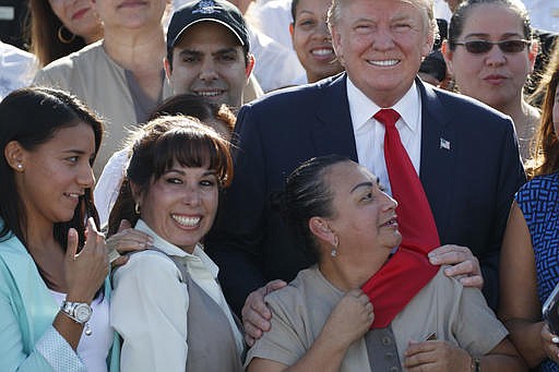 An employee of Republican presidential candidate Donald Trump grabs his tie as they pose for photographs during an event at Trump National Doral, Tuesday, Oct. 25, 2016, in Miami. 