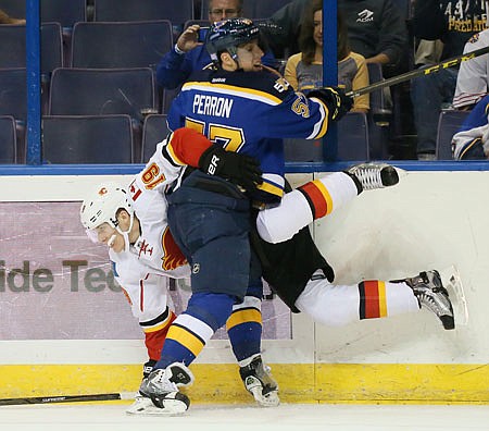 David Perron of the Blues knocks Matthew Tkachuk of the Flames into the boards during Tuesday night's game in St. Louis.