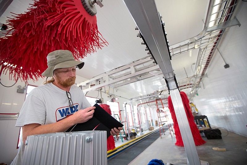 Troy Hollinger with Stacy Thornburg Services puts the cloth on one of the rocker rollers Tuesday in the wash tunnel of the new Boomerang Car Wash on State Line Avenue 