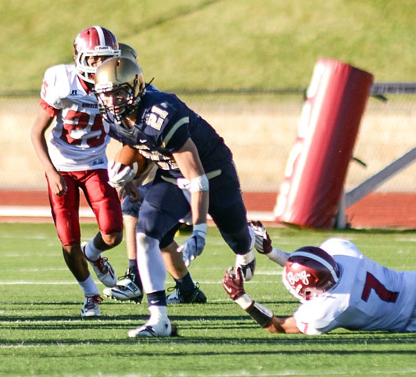 Helias running back Jacob Storms slips his feet through the hands of a Warrensburg defender for a big gain during last Saturday's game at Adkins Stadium.