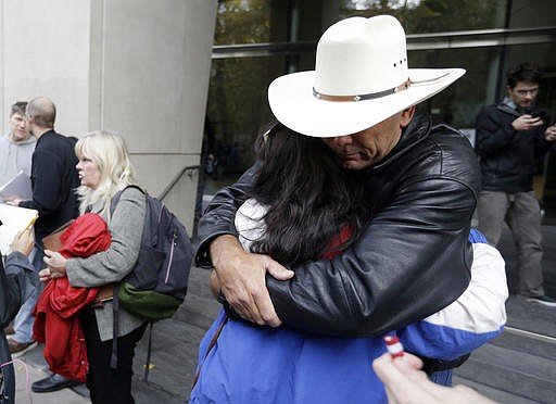 Defendant Shawna Cox speaks at left as supporters hug outside federal court in Portland, Ore., Thursday, Oct. 27, 2016. A jury exonerated brothers Ammon and Ryan Bundy and five others of conspiring to impede federal workers from their jobs at the Malheur National Wildlife Refuge.