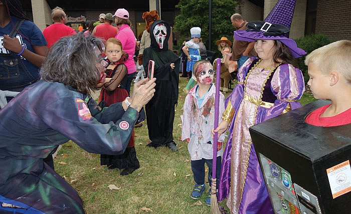 Celeste Suchanek, a communications operator at the Jefferson City Police Department, snaps a shot at some of the winners in Sunday's JCPD costume contest. The good witch in purple is Kaydence Turnbow and the vending machine in the foreground is Grant Ivy. Suchanek had her own impressive costume: a zombie guard.