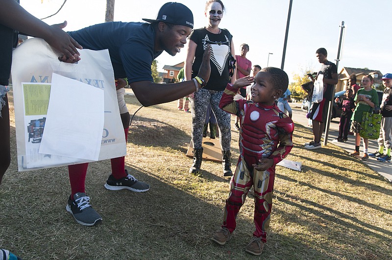 Juvard Anthony, left, high fives Jkarian Fisher, dressed as Iron Man, on Monday during a fall festival at Pecan Ridge at Rosehill Apartments.  The event was sponsored by Texarkana College and the Housing Authority of Texarkana, Texas.
