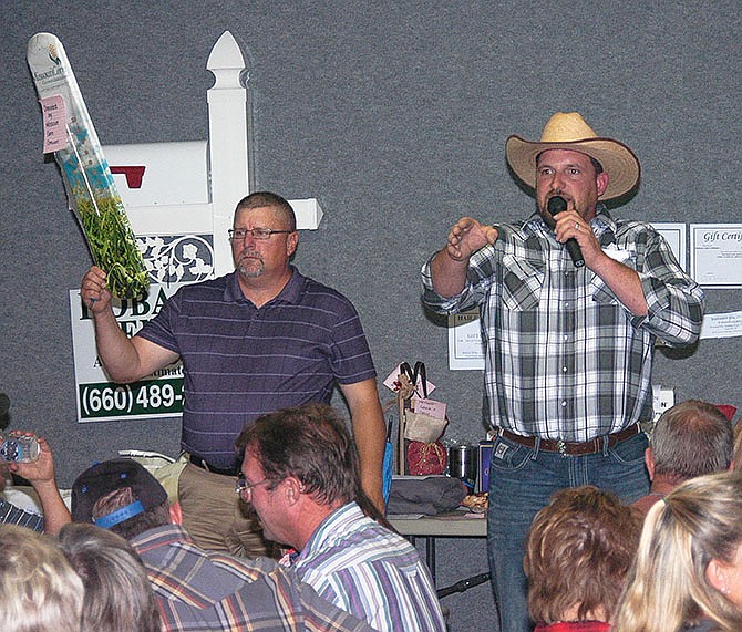 Auctioneer Grant Petree calls for bids on an outdoor thermometer held by Tom Huhmann at the Moniteau County Cattlemen's Dinner and Auction.