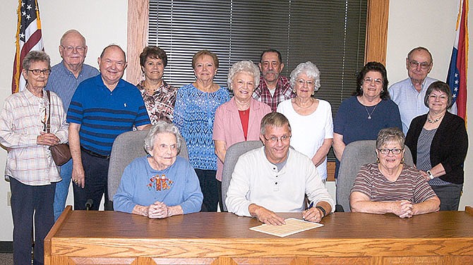 In recognition of the 50th anniversary of the Moniteau County Historical Society, Mayor Norris Gerhart signs a document proclaiming November a special time to show appreciation for the contributions of the organization. Present for the signing of the proclamation in California City Hall on are: front row, from left, Betty Williamson, Mayor Gerhart, Leah McNay; second row, Carol Schroeder, Paul Jungmeyer, Dorothy Jungmeyer, Dolores Burger, Dottie Gump, and Shirley Elliott; back row, Richard Schroeder, Beth Jungmeyer, Gloria Knipp, James Albin and Morris Burger.