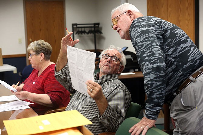 Gary Riddle, left, and Al Schmidt consult while counting absentee ballots from the military Tuesday at the Cole County Courthouse annex.