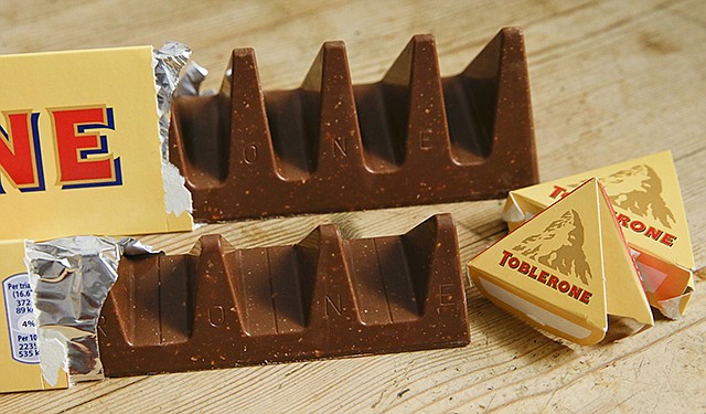 Shown at front is the new style 150-gram bar showing the reduction in triangular pieces, in the background is the older style 360-gram bar. More valleys, fewer chocolate peaks: The maker of Toblerone Swiss chocolate said it has widened the spaces in its iconic, triangle-array bars for some discount shops in Britain to keep prices down. Mondelez International said the move aims to meet pricing targets by customer Poundland and other discount retailers, and has nothing to do with Britain's vote to leave the European Union.
