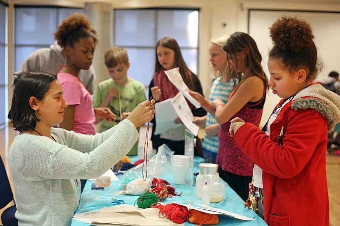 Vara Om, left, helps Amira Maute, 11, make a DNA necklace during Building with Biology on Tuesday at Lincoln University. The event was part of a nationwide festival of educational programs designed to encourage conversations between the public and scientists. Om is a pre-medical student at Lincoln University.