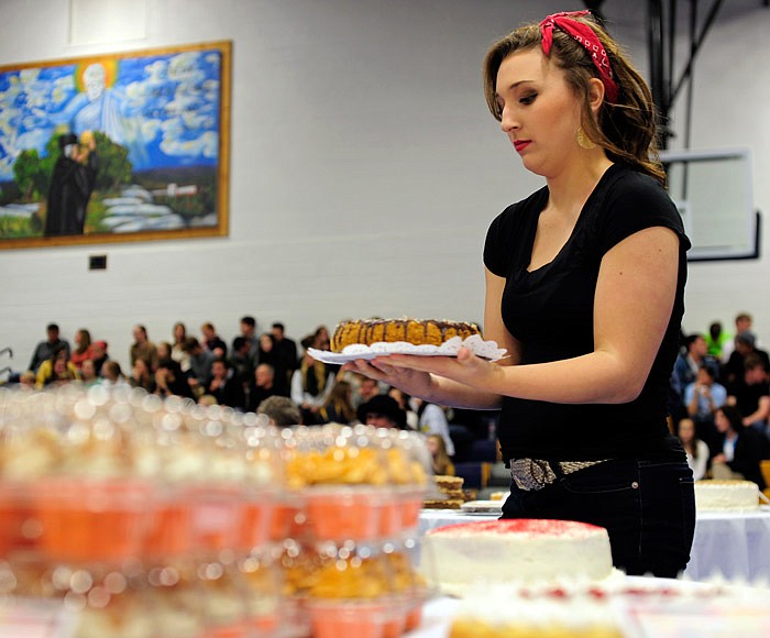 In this Nov. 25, 2014 file photo, Helias show choir member Mikayla Pitera gets set to walk a chocolate coconut almond cheesecake through the crowd as it goes on the auction block during the "Just Desserts" fundraiser benefiting the Helias Impact Show Choir.
